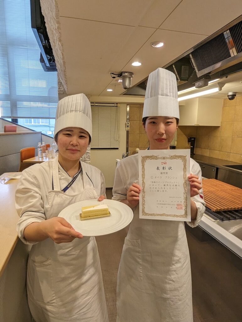 学校法人村川学園大阪調理製菓専門学校の生徒たちは試作を重ねたメニューをプレゼンテーション。優秀賞に選ばれた「オペラ　ブランシュ」を筆頭に、複数の限定スイーツが展開される。