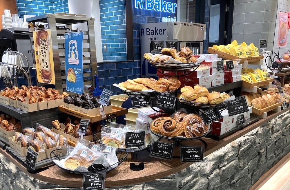 8月9日、「R Baker mini エキュート立川店」がオープンした。オープン記念として8月末まで「産地直送まるごと！もものクロワッサン」を数量限定で販売する。価格は580円。