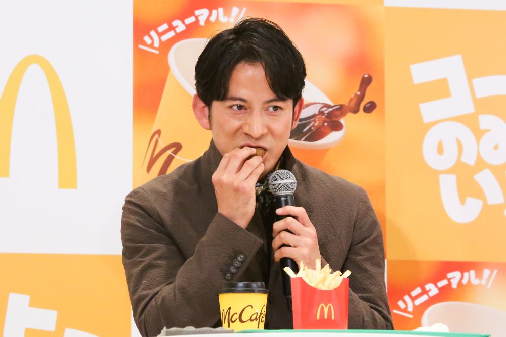 赤木裕さんから手渡された「クリームブリュレホットドーナツ」を試食する岡田准一さん