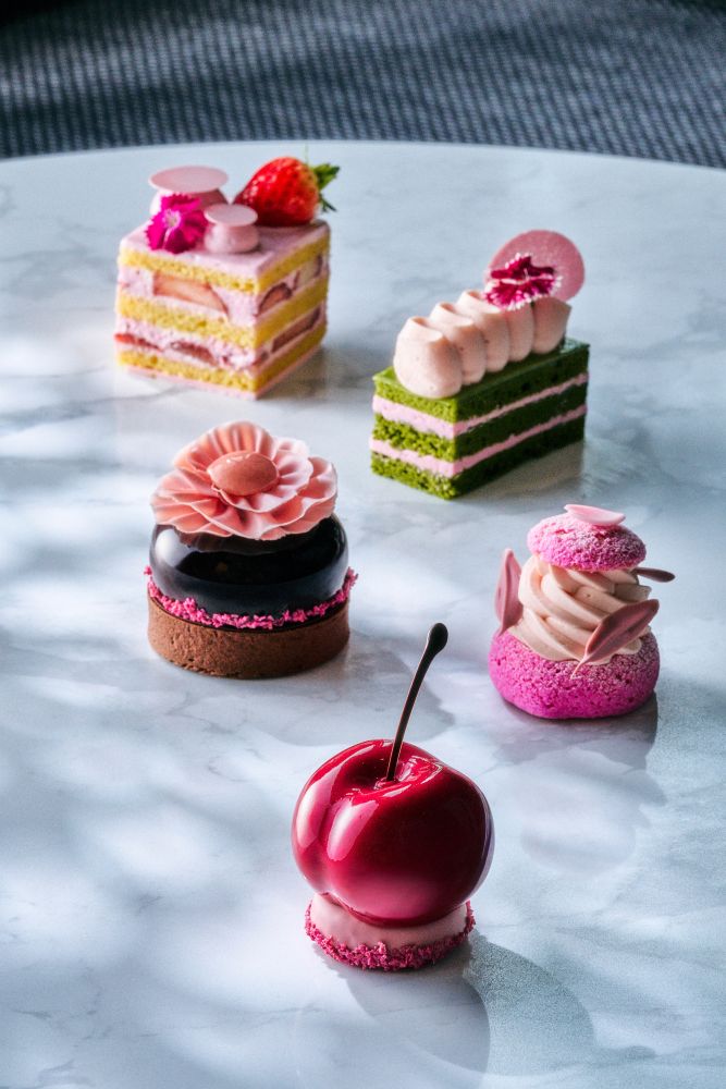 奥から「桜ストロベリーショートケーキ」税込み1,200円、「抹茶と桜のオペラケーキ」税込み1,200円、「70％ダークチョコレートと桜のタルト」税込み1,600円、「マカダミアナッツと桜のパリブレストシュー」税込み1,250円、「チェリーと桜のケーキ」税込み1,300円