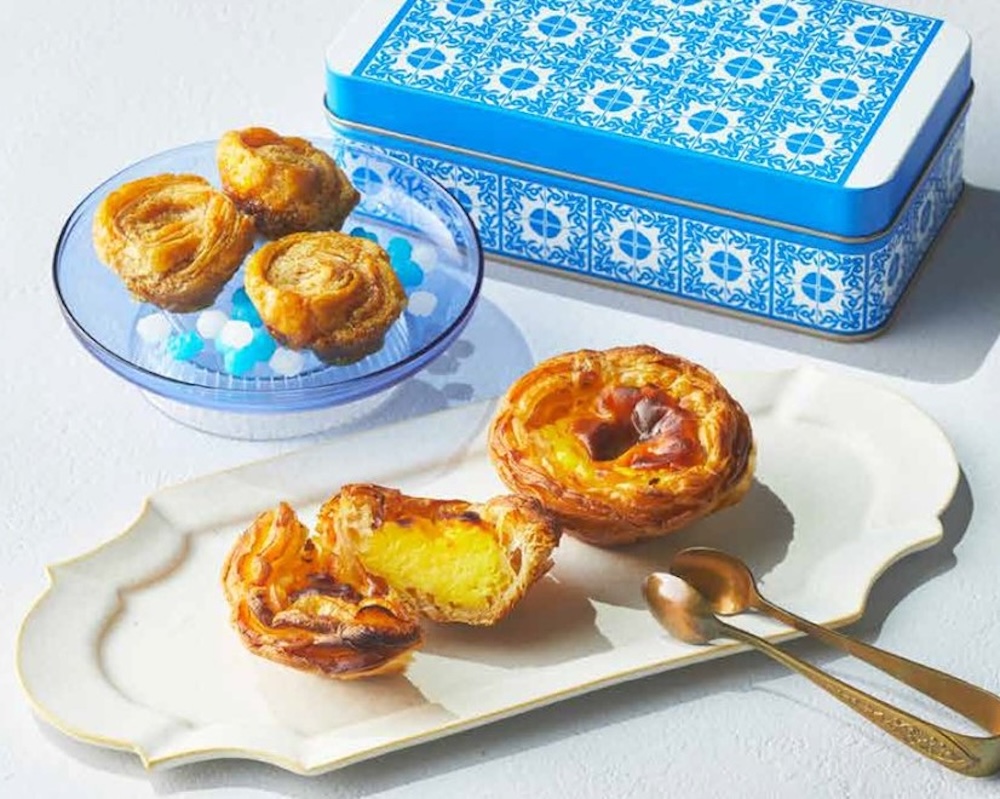 5月3日のみ販売される「ナタ・デ・クリスチアノ」の「パステル・デ・ナタ〈エッグタルト〉」1個・301円、「ノビタ〈クッキー缶〉」2,421円