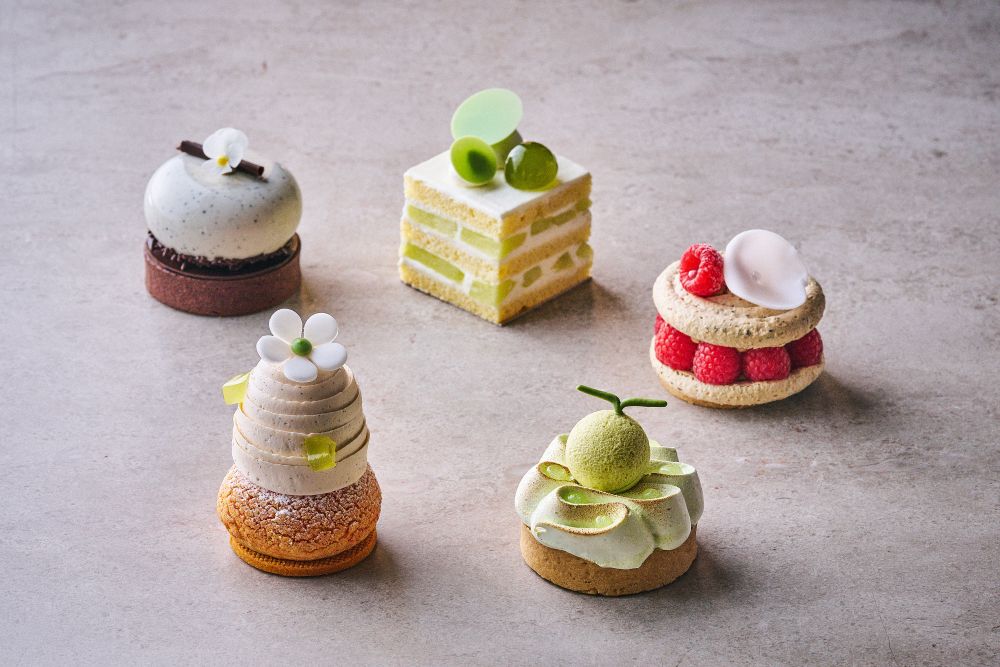 左奥から時計回りに「ほうじ茶と麦茶のなめらかチョコレートタルト」税込み1,650円、「メロンショートケーキ」税込み1,200円、「ほうじ茶ラズベリーマカロン」税込み1,300円、「メロンとライムメレンゲタルト」税込み1,450円、「赤肉メロンとベルガモットシュークリーム」税込み1,300円