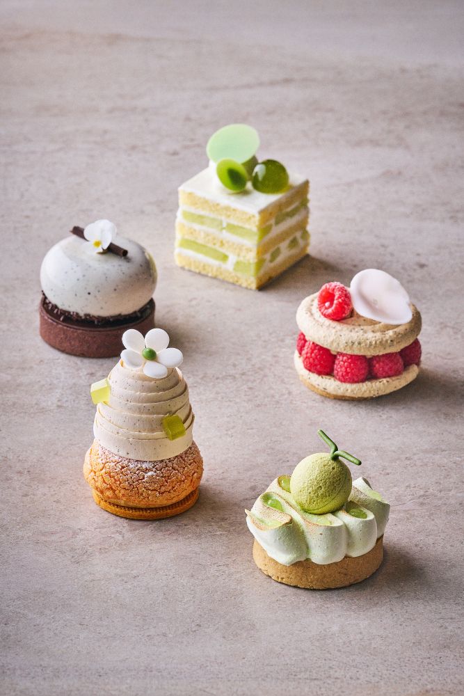 左奥から時計回りに「ほうじ茶と麦茶のなめらかチョコレートタルト」税込み1,650円、「メロンショートケーキ」税込み1,200円、「ほうじ茶ラズベリーマカロン」税込み1,300円、「メロンとライムメレンゲタルト」税込み1,450円、「赤肉メロンとベルガモットシュークリーム」税込み1,300円