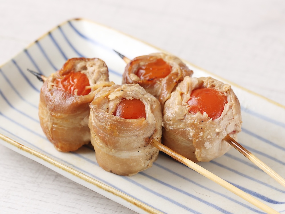 「串くら」の各日30本限定「プチトマトの豚巻き串」1本・税込み390円
